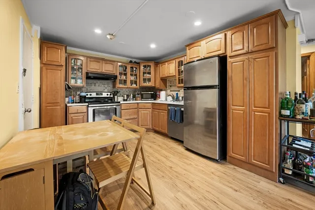a kitchen with stainless steel appliances granite countertop a refrigerator a stove top oven a sink dishwasher and wooden cabinets with wooden floor