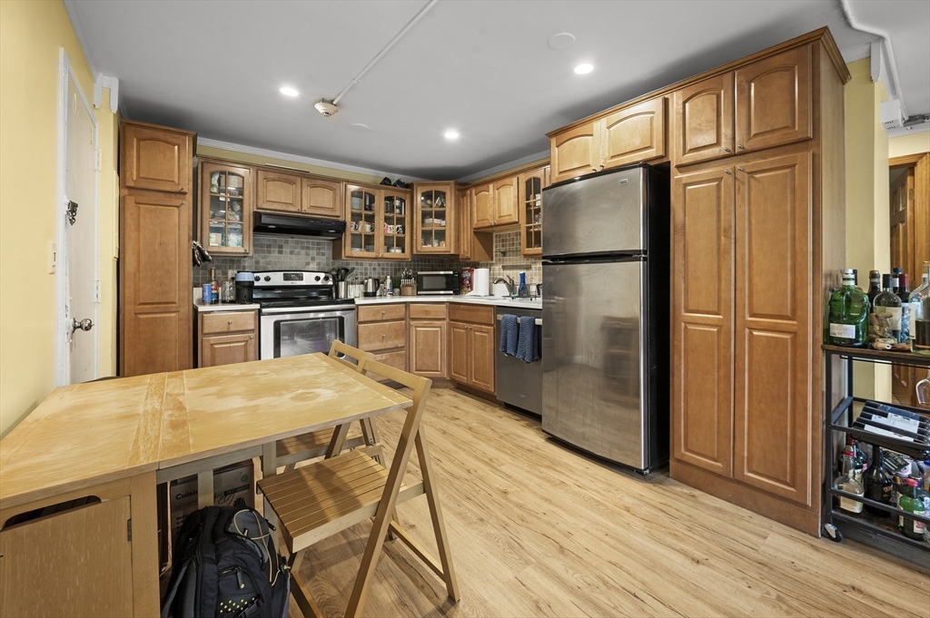 70 Jamaicaway, Unit 1 Boston, MA 02130 - Photo 5 of 19 a kitchen with stainless steel appliances granite countertop a refrigerator a stove top oven a sink dishwasher and wooden cabinets with wooden floor