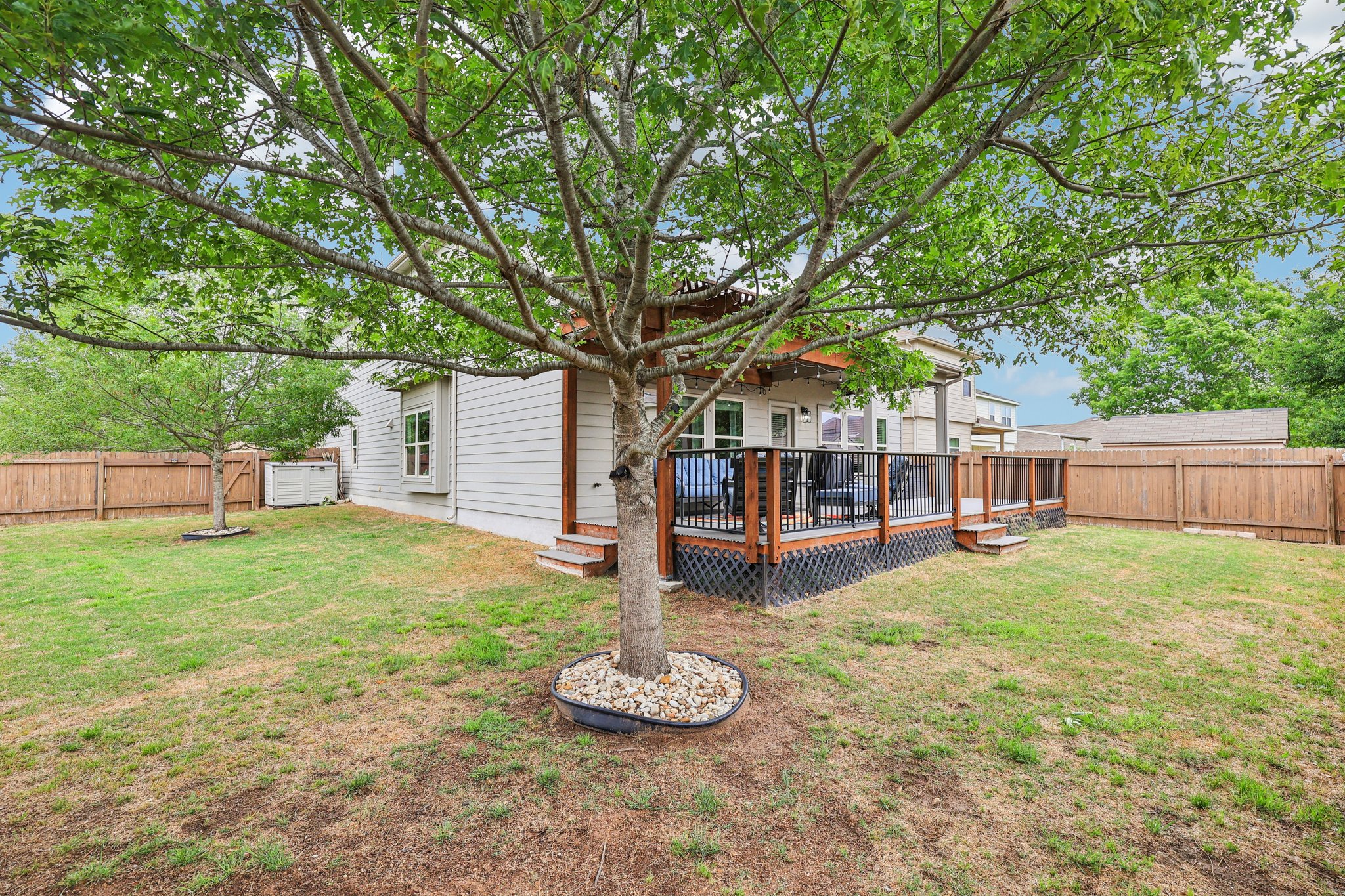 10033 Gertrudis Loop Austin, TX 78747 - Photo 27 of 39 The property features an extensive backyard with a lawn and mature trees, surrounded by a wooden privacy fence