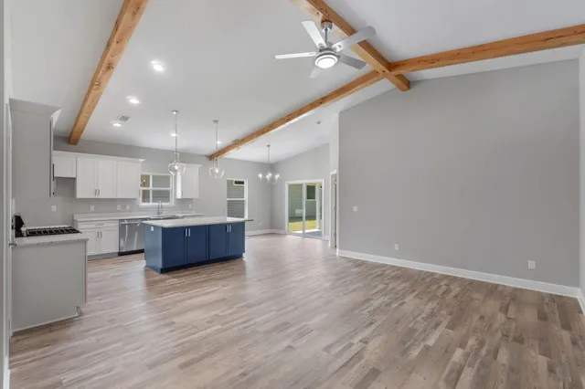 a large kitchen with stainless steel appliances a large counter top a stove and a wooden floor