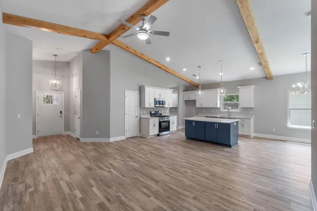 a large white kitchen with kitchen island a sink stainless steel appliances and cabinets