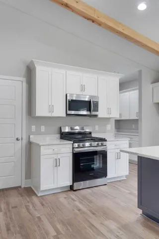 a kitchen with stainless steel appliances granite countertop a stove and white cabinets