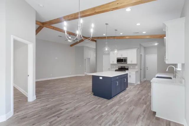 a large kitchen with a large counter top a sink stainless steel appliances and cabinets