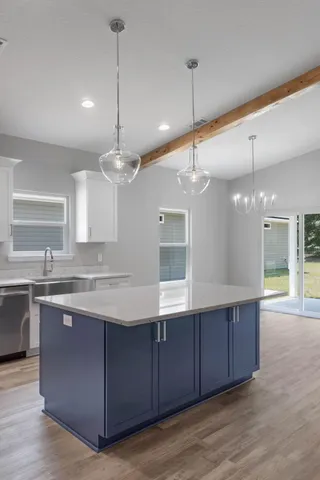 a open kitchen with a sink and dishwasher with wooden floor