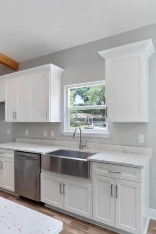 a kitchen with white cabinets and a window