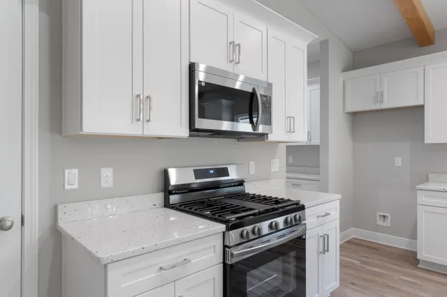 a kitchen with stainless steel appliances granite countertop white cabinets and a stove top oven