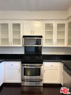 a kitchen with granite countertop white cabinets and appliances