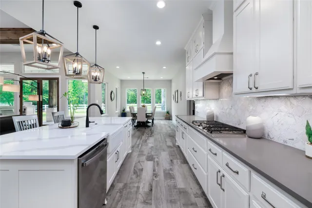 a kitchen with stainless steel appliances granite countertop a sink a stove a dining table and chairs