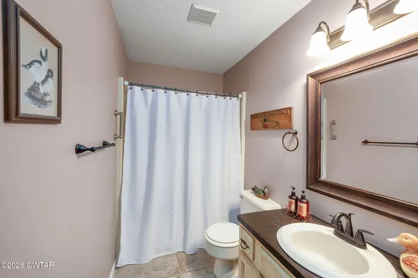 a bathroom with a granite countertop sink toilet and mirror