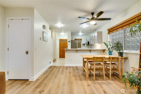 a dining room with stainless steel appliances a dining table chairs and wooden floor
