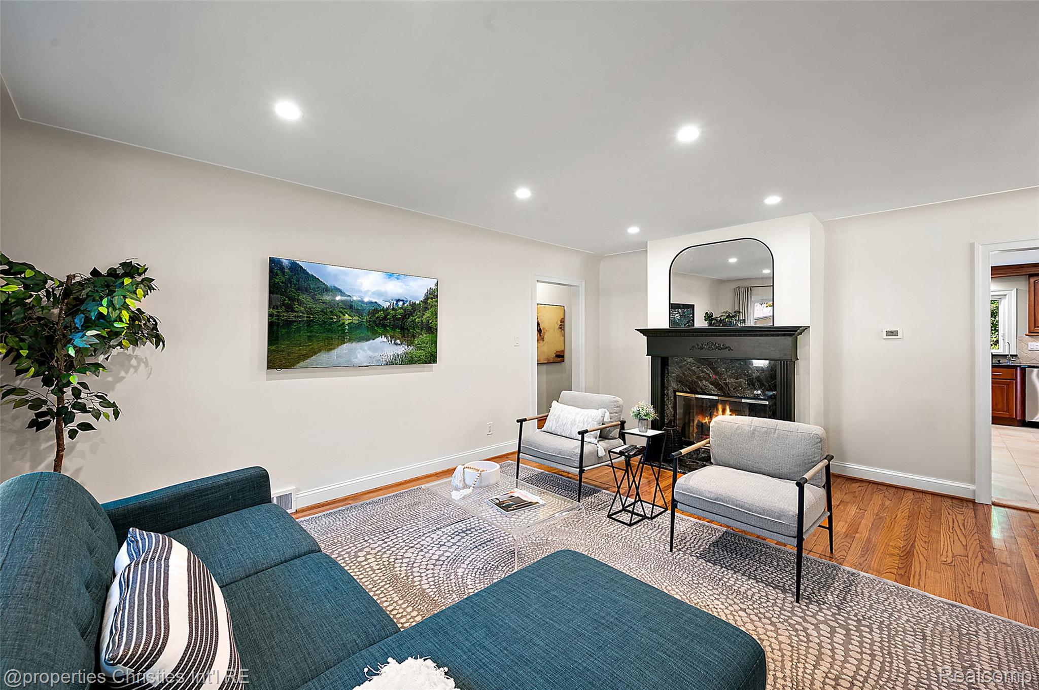 27331 Gardenway Road Franklin, MI 48025 - Photo 24 of 65 Living area featuring a fireplace with a dark stone surround and black mantel, recessed lighting, wood-finish flooring, and light-toned walls