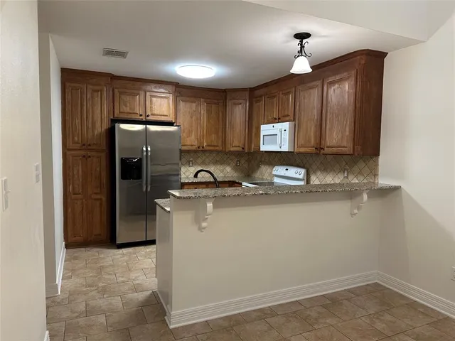 a kitchen with stainless steel appliances granite countertop a refrigerator a stove a sink and a microwave