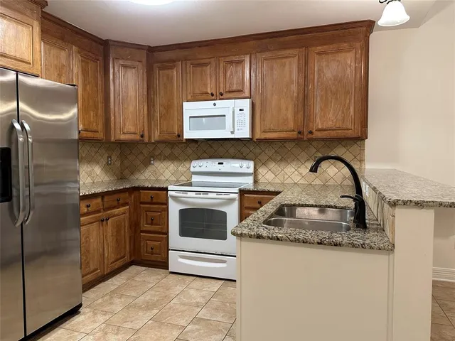 a kitchen with granite countertop a sink stainless steel appliances and cabinets