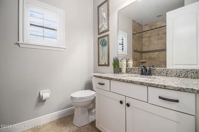 a bathroom with a granite countertop sink toilet and mirror