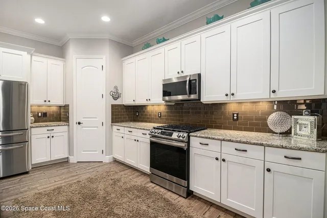 a kitchen with granite countertop white cabinets and stainless steel appliances