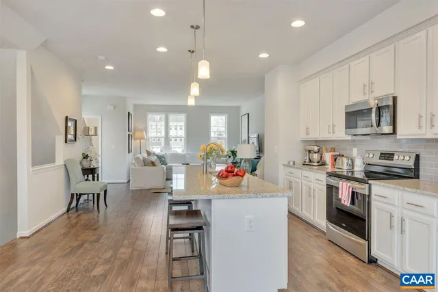 a open kitchen with stainless steel appliances granite countertop a stove top oven a sink dishwasher and white cabinets with wooden floor