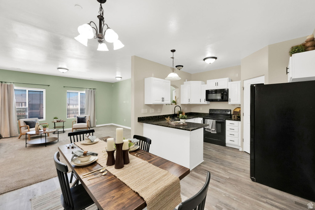 8215 Clear Rock Road, Unit 12 Eagle Mountain, UT 84005 - Photo 8 of 38 Open-concept dining area and kitchen featuring wood-finish flooring, white cabinetry, dark countertops, and black appliances