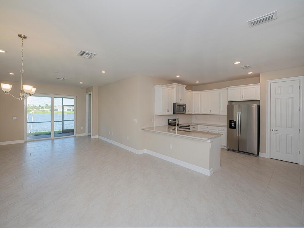 a view of an empty room with kitchen stove and a refrigerator