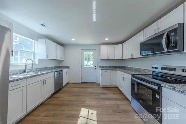 a large kitchen with stainless steel appliances granite countertop a stove sink and microwave