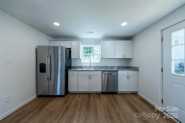 a kitchen with granite countertop a refrigerator and a sink
