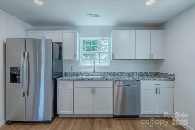 a kitchen with stainless steel appliances granite countertop a refrigerator and wooden cabinets