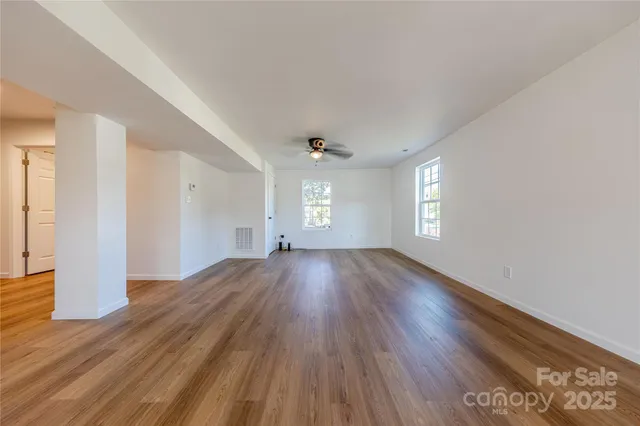 a view of empty room with window and wooden floor