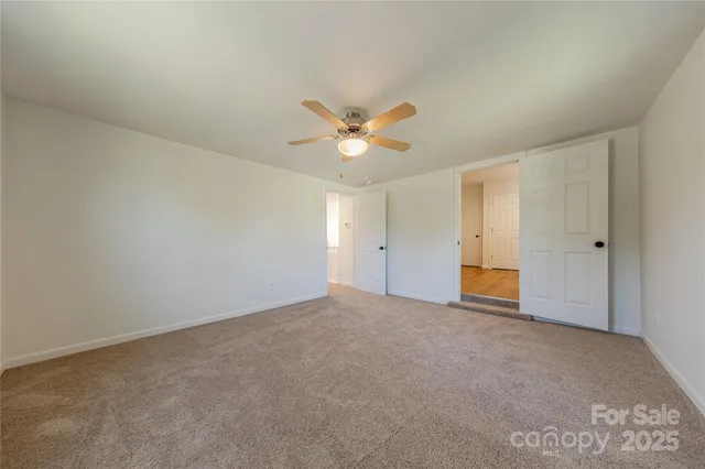 an empty room with closet and ceiling fan
