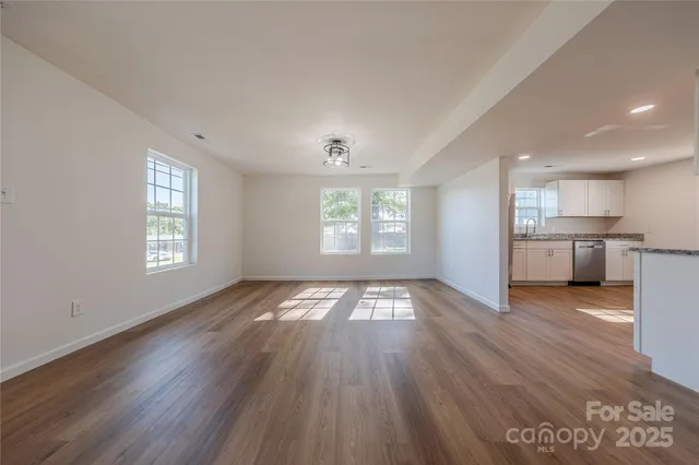a view of empty room with kitchen and window