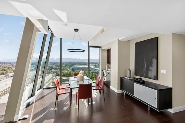 a living room with stainless steel appliances furniture a dining table and a chandelier