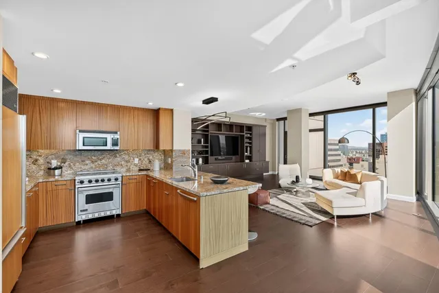 a dining hall with stainless steel appliances granite countertop a couch a dining table and chairs with wooden floor