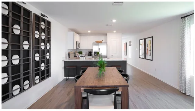 a kitchen with stainless steel appliances a sink a stove a refrigerator with white cabinets and wooden floor