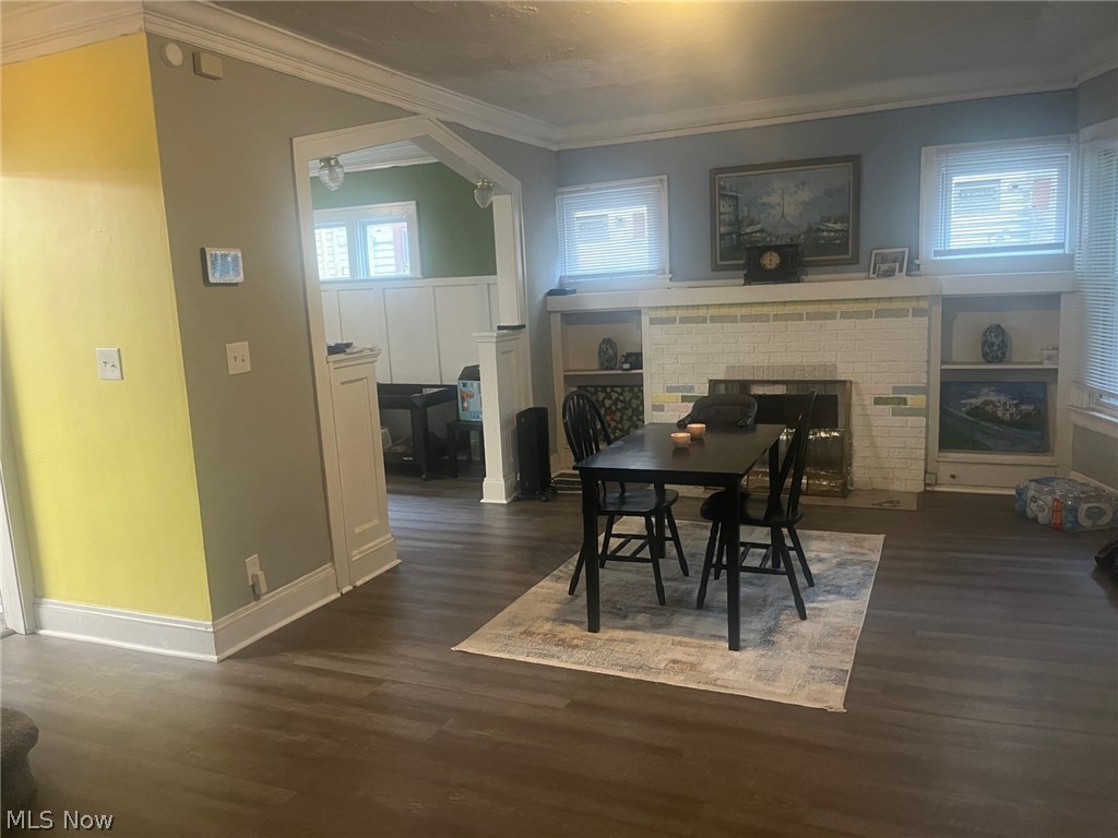 1101 Carlyon Road East Cleveland, OH 44112 - Photo 3 of 23 Living space featuring new flooring, a fireplace with a white brick surround, built-in shelving, crown molding, and an arched entry to an additional room