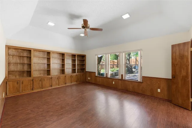 a view of an empty room with a window and wooden floor