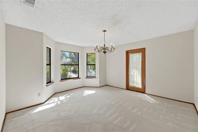 a view of a big room with windows and chandelier fan