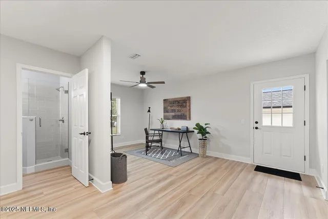 a view of empty room with wooden floor and fan