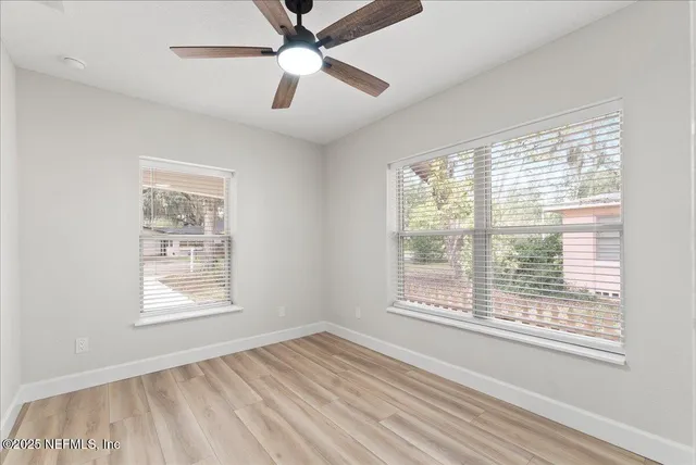 an empty room with a window and a fan