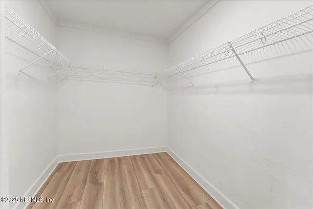 an empty room with wooden floor ceiling fan and windows