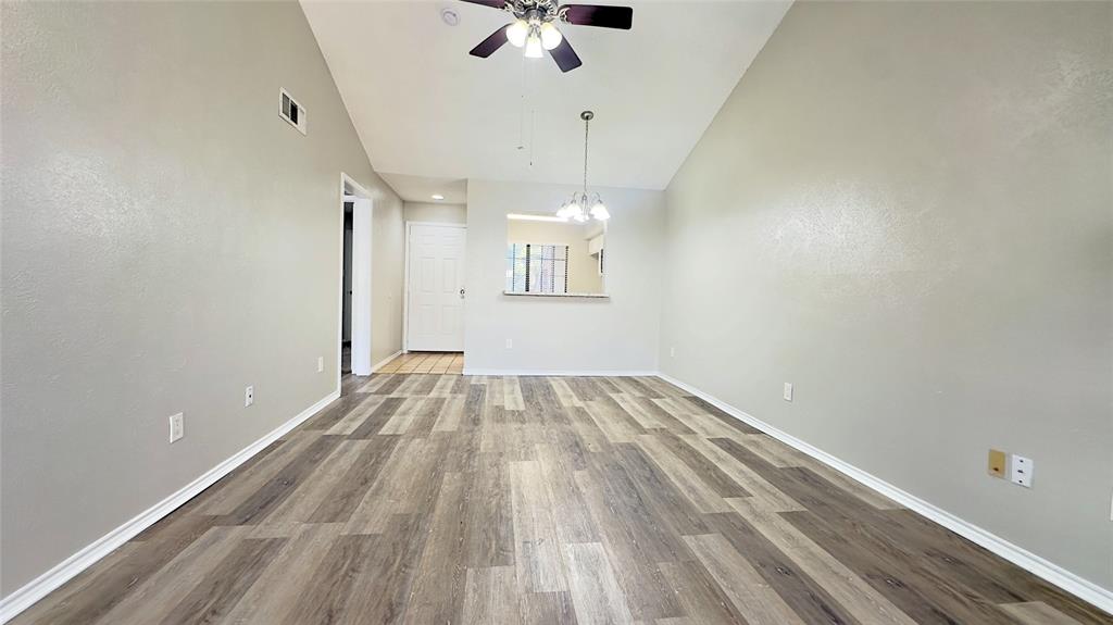 9601 Forest Lane, Unit 323 Dallas, TX 75243 - Photo 6 of 23 Unfurnished living room featuring wood finished floors, a chandelier, a ceiling fan, and high vaulted ceiling