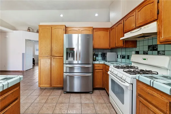 a kitchen with stainless steel appliances granite countertop a stove a refrigerator and a stove top oven