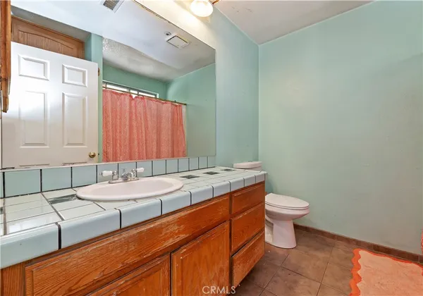 a bathroom with a granite countertop sink a toilet and mirror