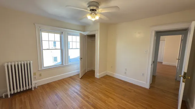 an empty room with wooden floor fan and windows