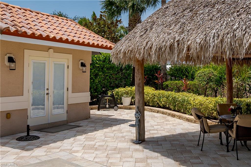 13419 Snook Circle Naples, FL 34114 - Photo 11 of 34 a view of a patio with table and chairs a barbeque with potted plants and palm trees