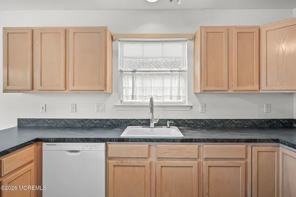 a kitchen with granite countertop white cabinets sink and window