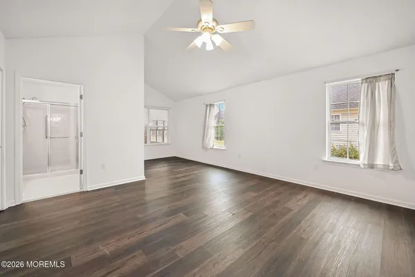 an empty room with wooden floor chandelier fan and windows