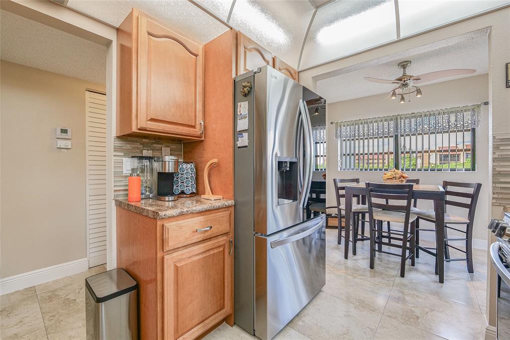 3650 Environ Boulevard, Unit 401 Lauderhill, FL 33319 - Photo 15 of 59 a kitchen with stainless steel appliances granite countertop a stove a refrigerator a dining table and chairs with wooden floor