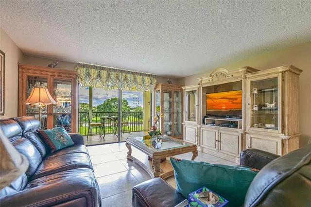 a living room with furniture a flat screen tv and a floor to ceiling window