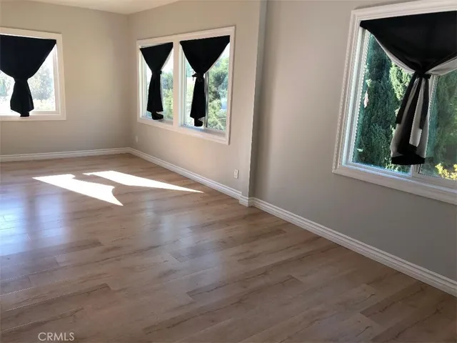 an empty room with wooden floor and windows