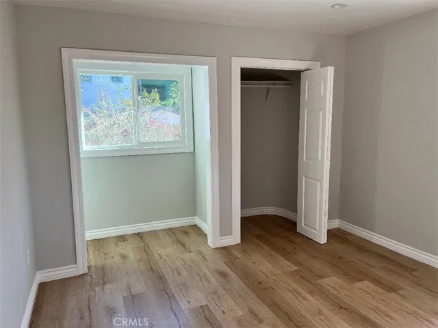 an empty room with wooden floor painting and windows