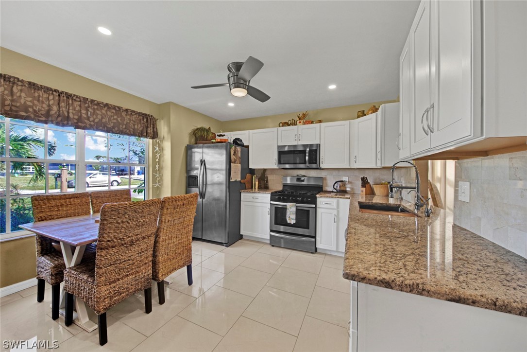 18442 Sunflower Road Fort Myers, FL 33967 - Photo 8 of 26 a kitchen with stainless steel appliances granite countertop a refrigerator a sink dishwasher a stove and white cabinets with wooden floor