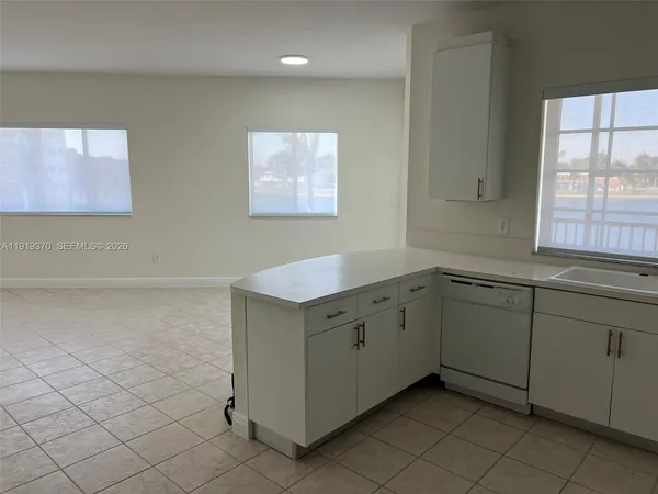 a large white kitchen with a sink and cabinets